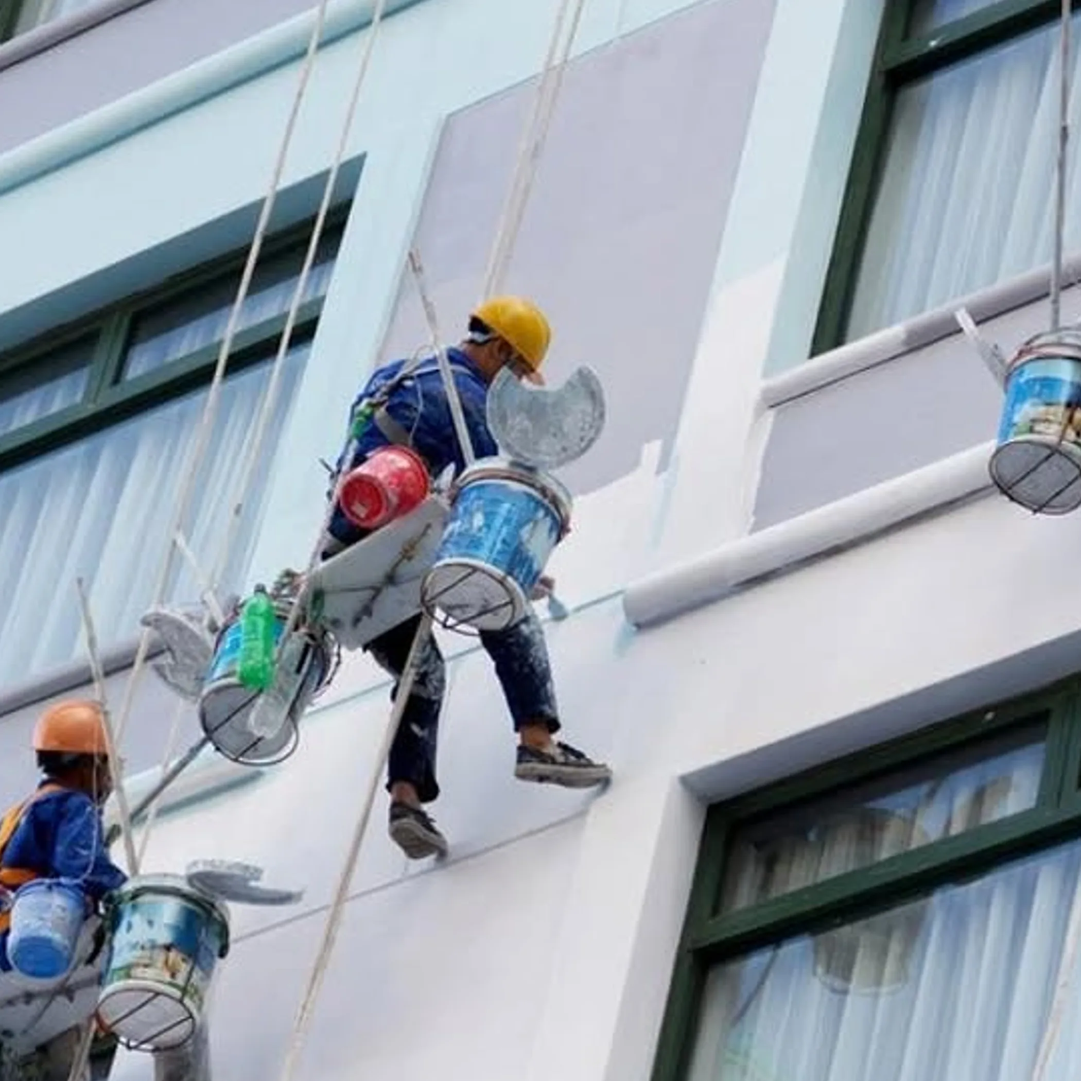workers performing building maintenance with ropes